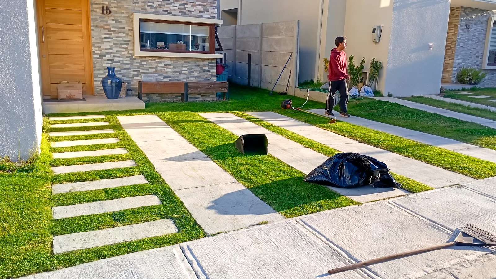 Antejardín con franjas de pasto natural recién instalado entre losetas de hormigón